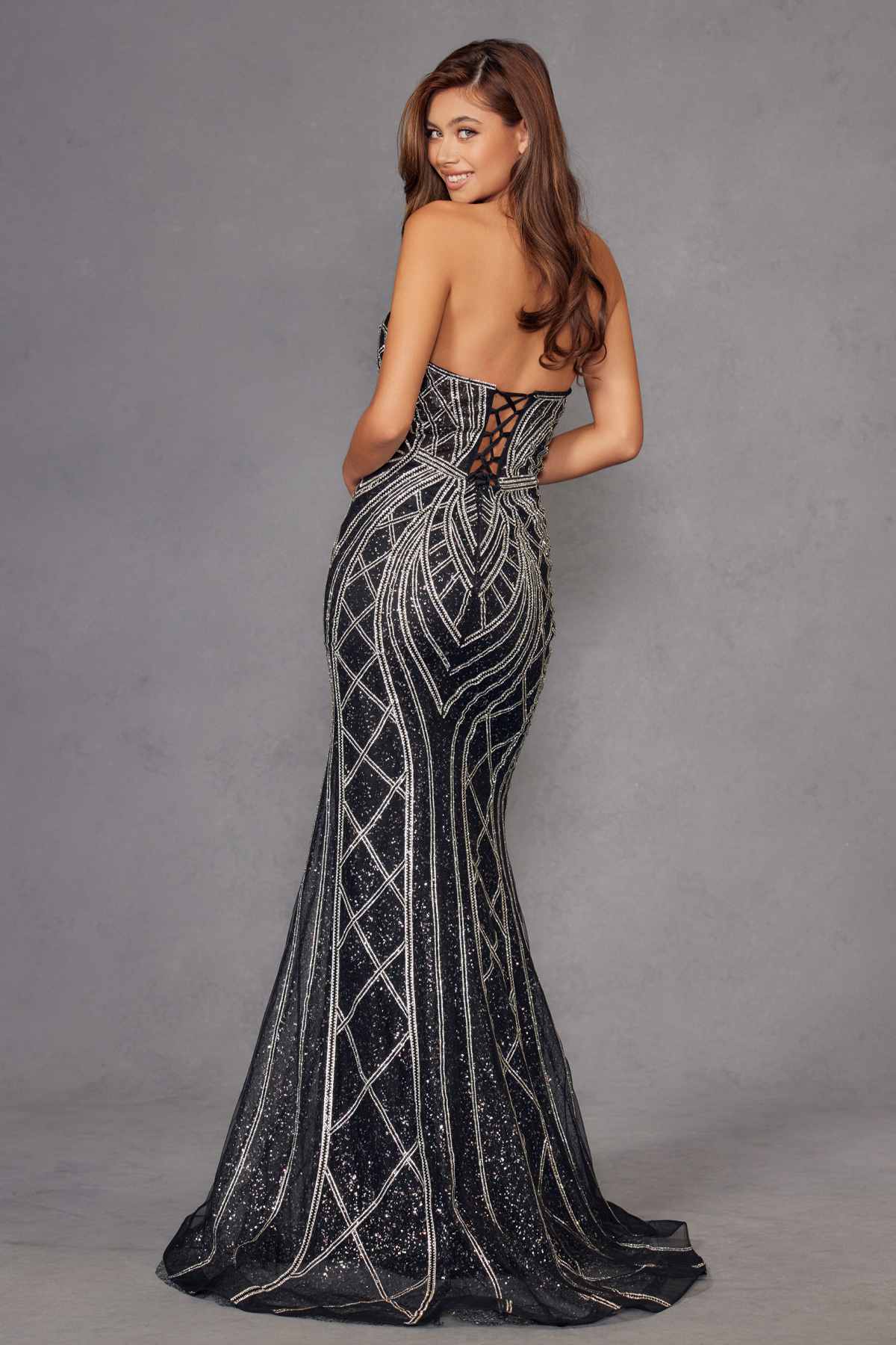 Strapless fitted evening gown with silver geometric beadwork on dark fabric, floor-length.