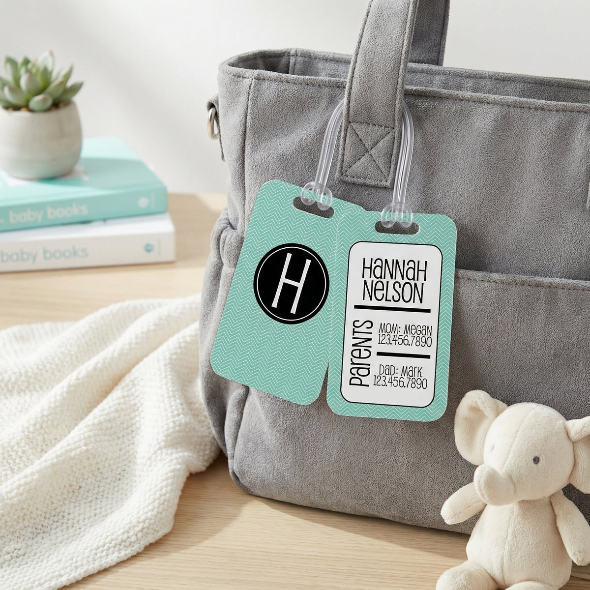 Personalized diaper bag tag on gray bag, teal chevron label with monogram H and name