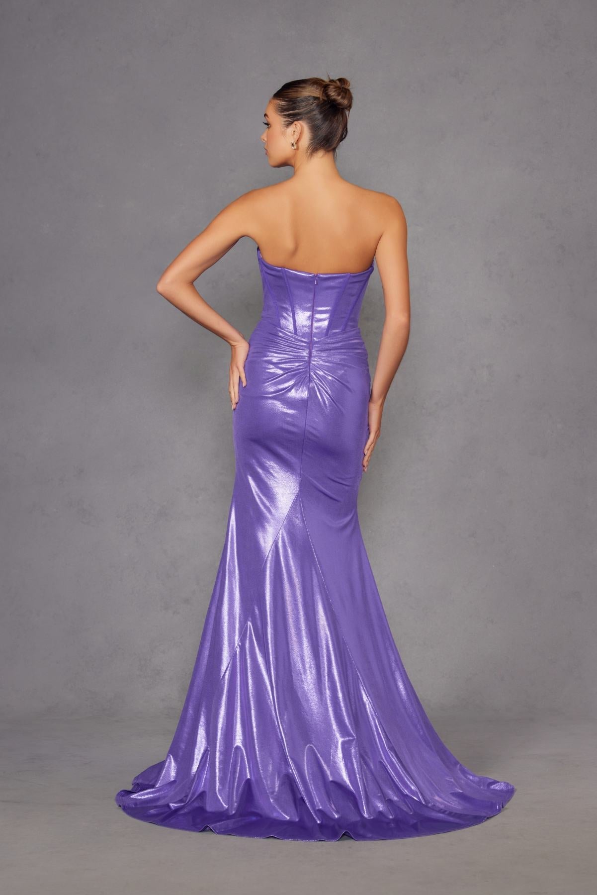 Purple strapless fitted metallic prom gown with ruched back detail and flowing mermaid hem.