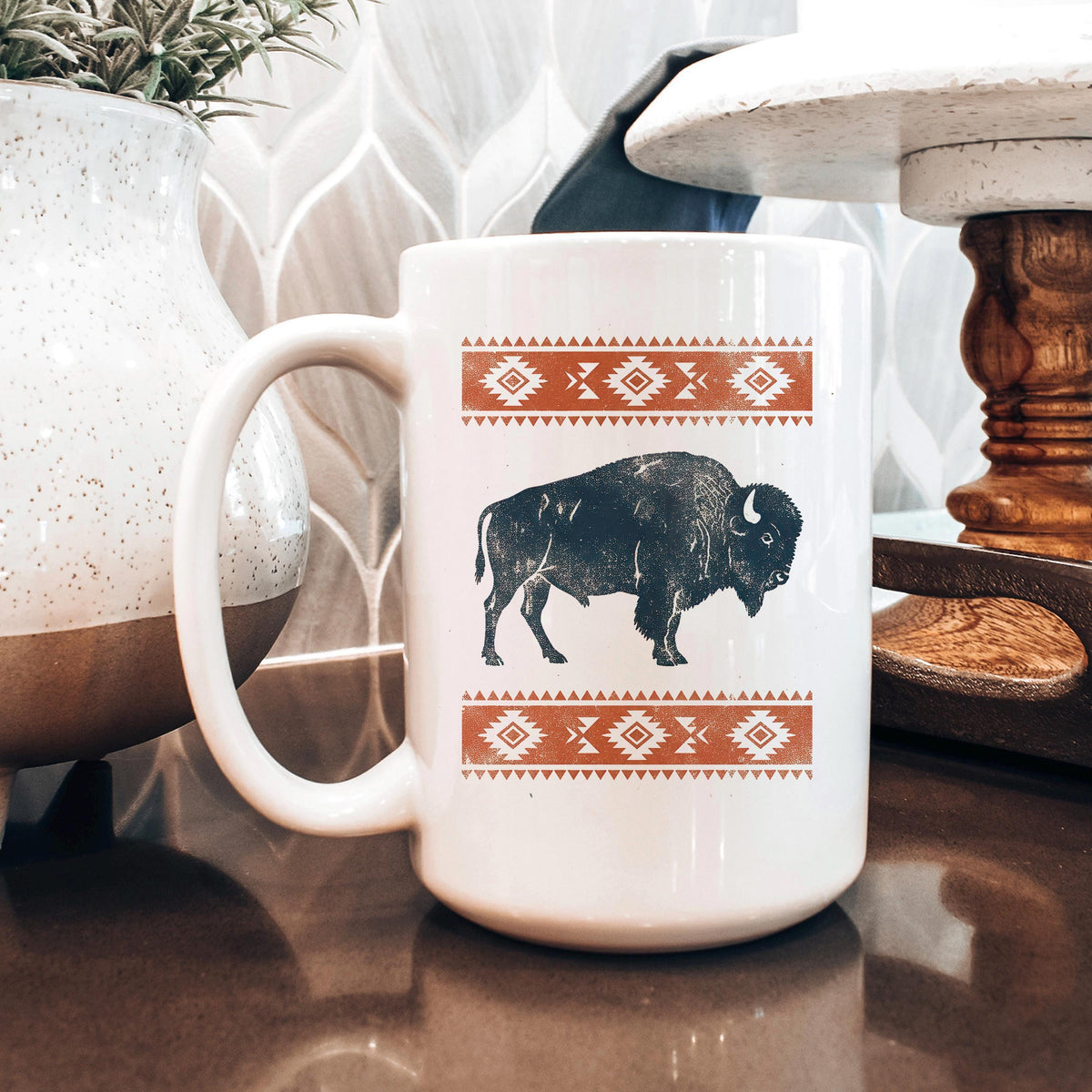 White ceramic mug with black bison print and orange southwest border design