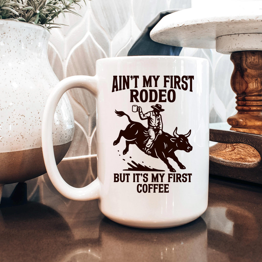 White ceramic coffee mug with rodeo quote and bull rider graphic on front.