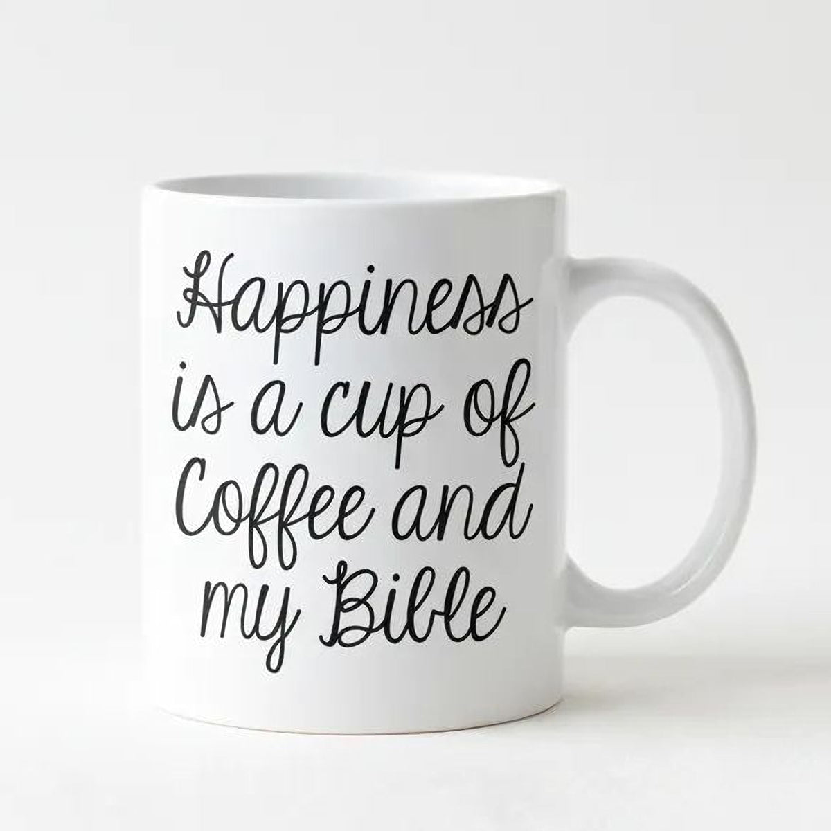 White ceramic coffee mug with black script: 'Happiness is a cup of coffee and my Bible'