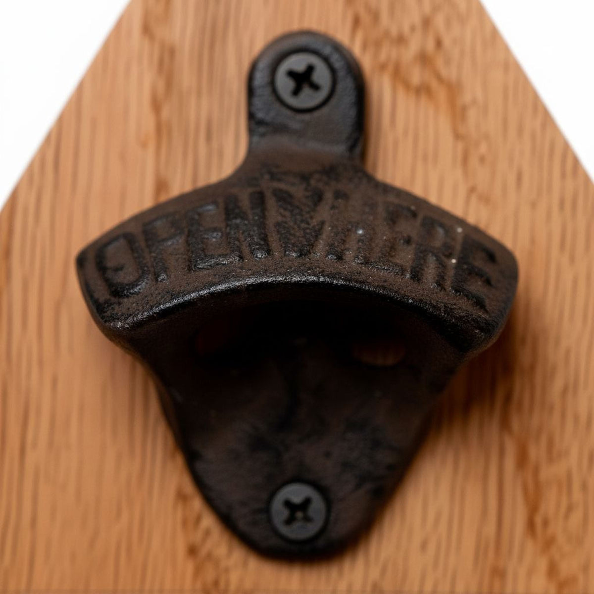 Close-up of metal bottle opener mounted on a wood garage sign