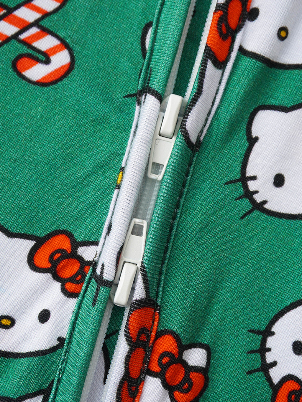 Green baby romper zipper close-up with white zipper teeth and Hello Kitty icon print