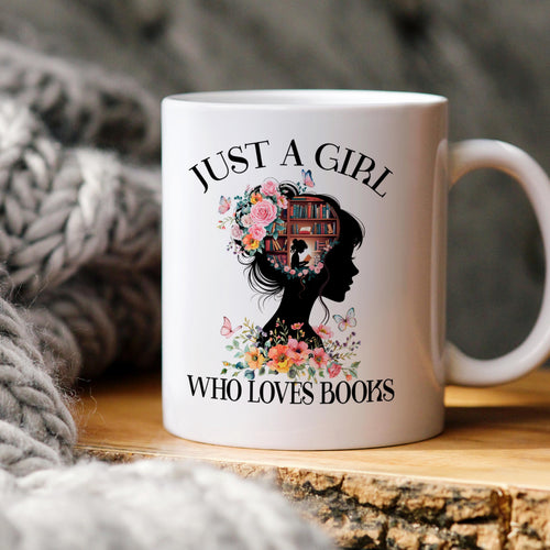 White ceramic coffee mug with “JUST A GIRL WHO LOVES BOOKS” graphic and floral book illustration.