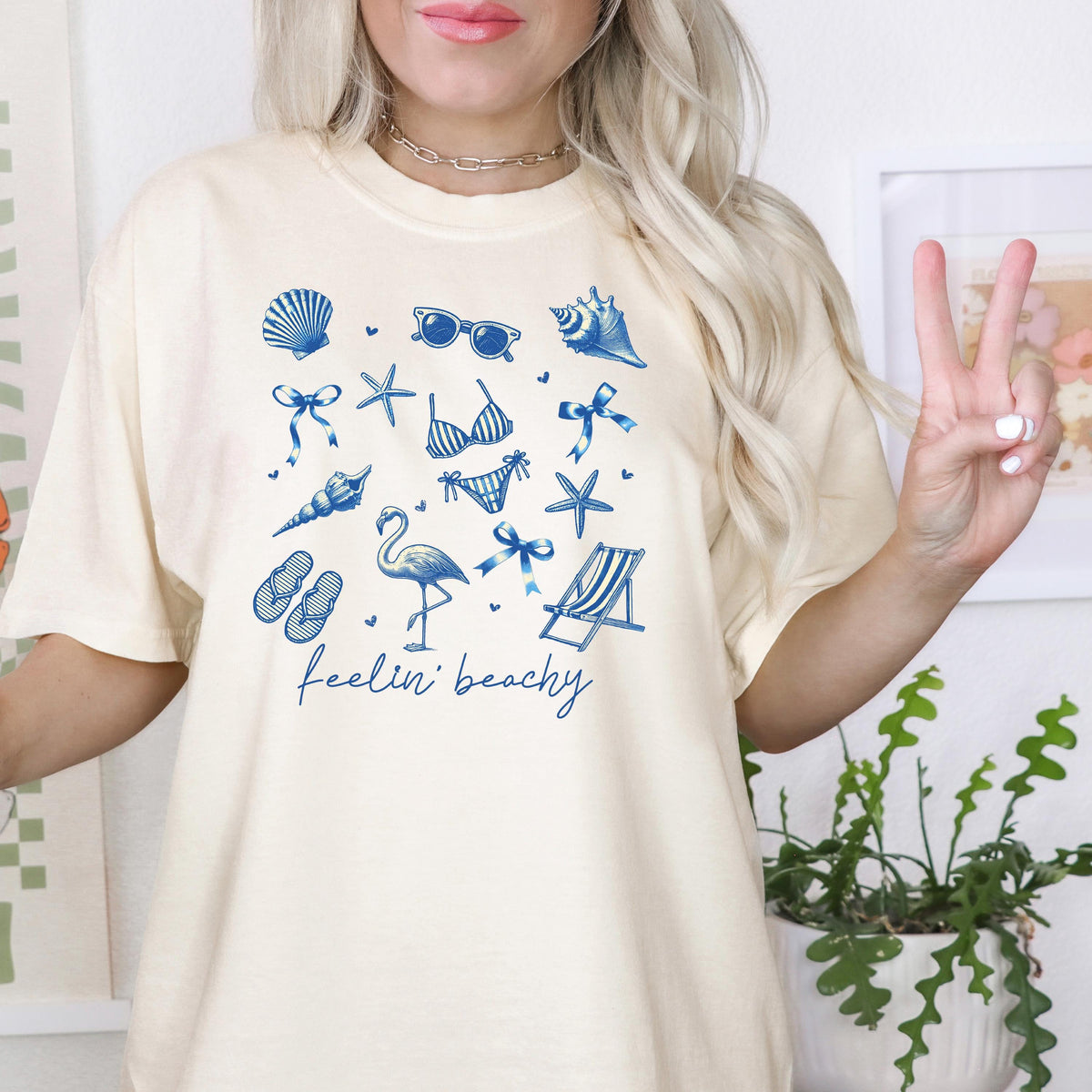 Ivory beach graphic unisex tee with blue coastal icons and “feelin’ beachy” print