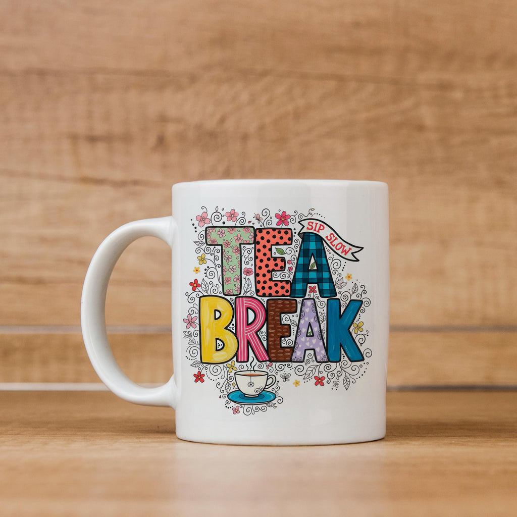 White ceramic tea mug with 'TEA BREAK' graphic, handle visible, colorful floral details