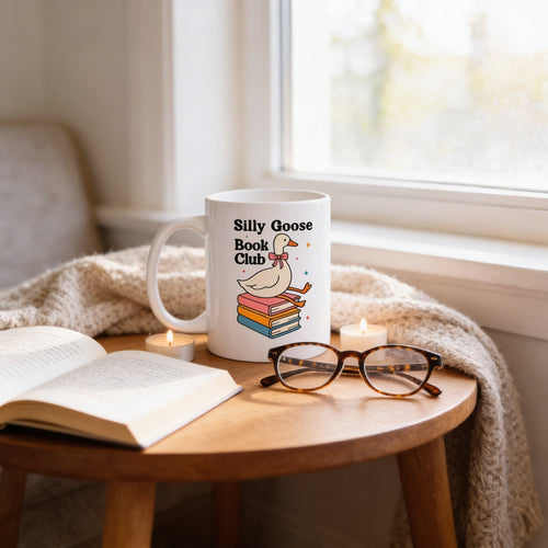 White ceramic coffee mug with goose-and-books graphic and 'Silly Goose Book Club' text.