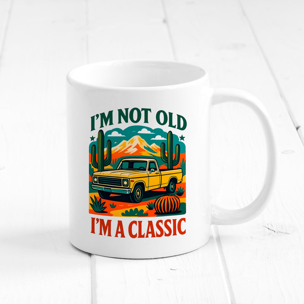 White ceramic mug with front graphic of vintage car and cacti; “I’m not old, I’m a classic”.