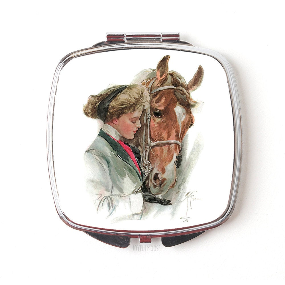 Close-up of square silver compact mirror with vintage horse-and-trainer illustration