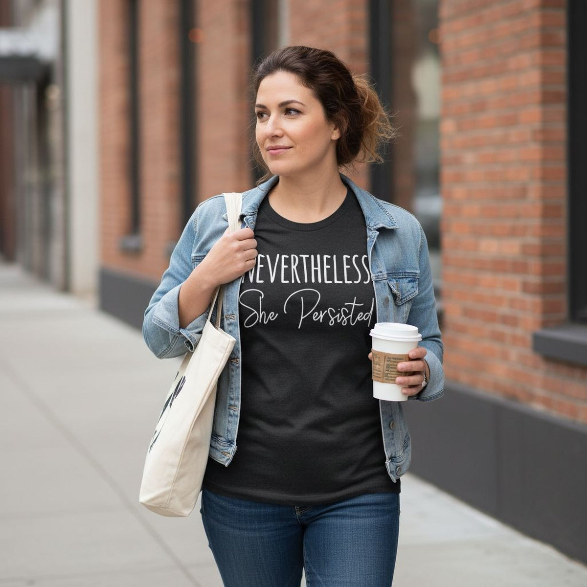 Black women's graphic tee with 'Nevertheless, She Persisted' print, worn with denim