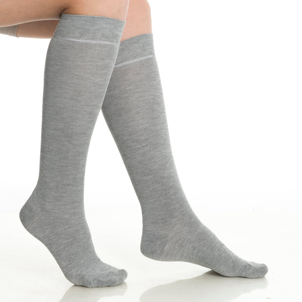 Pair of gray knee-high socks on feet, crew-to-calf coverage