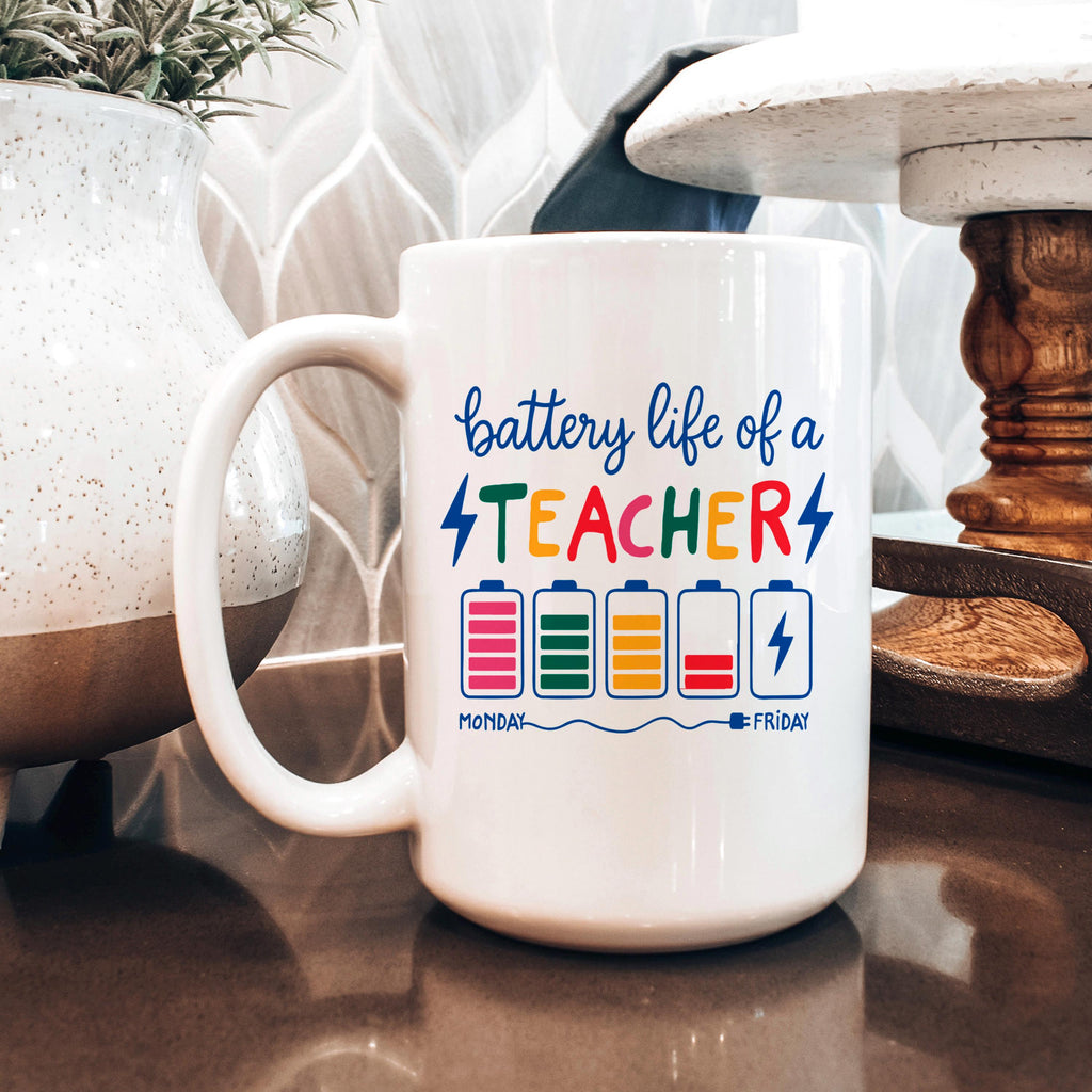 White ceramic mug with “battery life of a TEACHER” battery graphic on desk