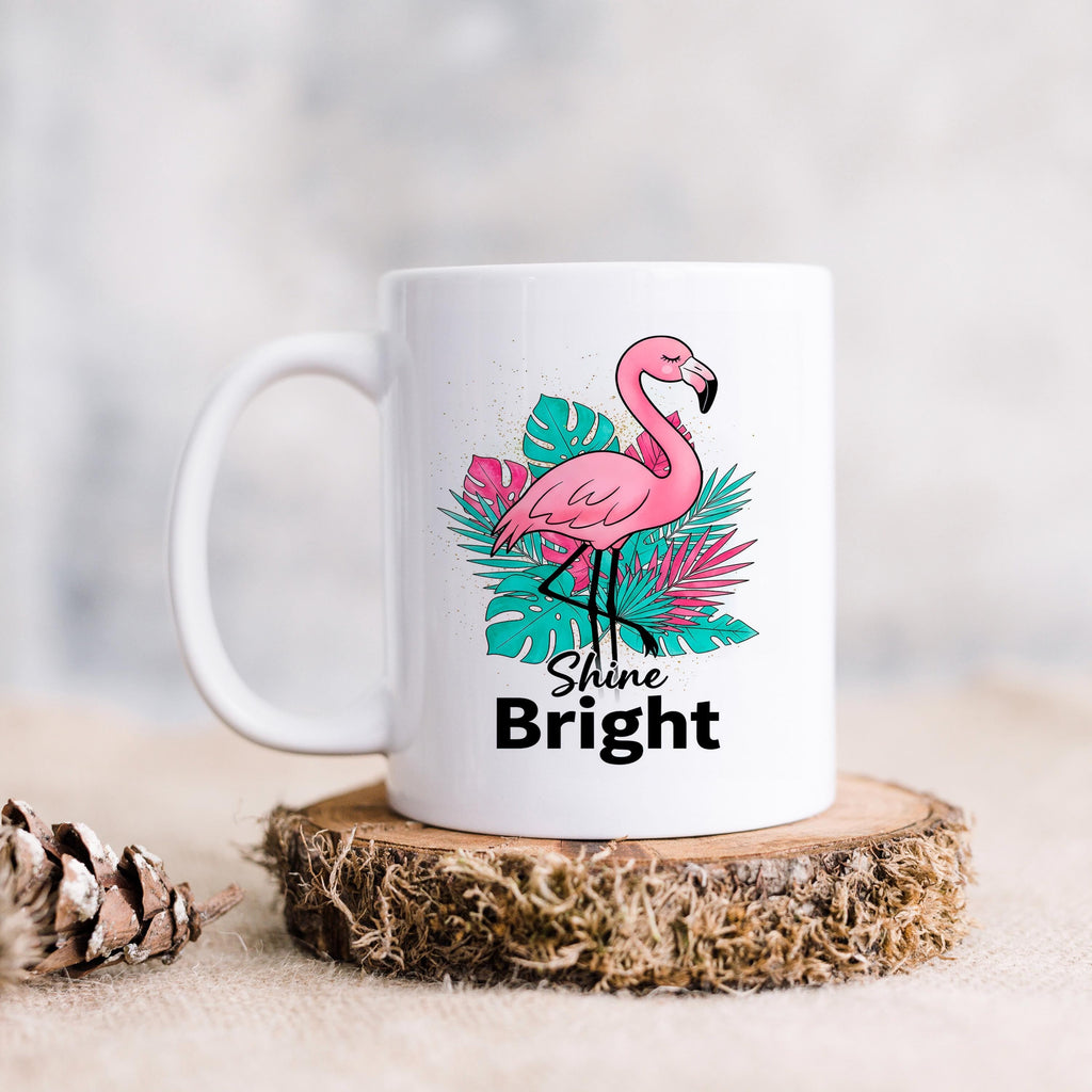 White ceramic mug with pink flamingo graphic and “Shine Bright” wording