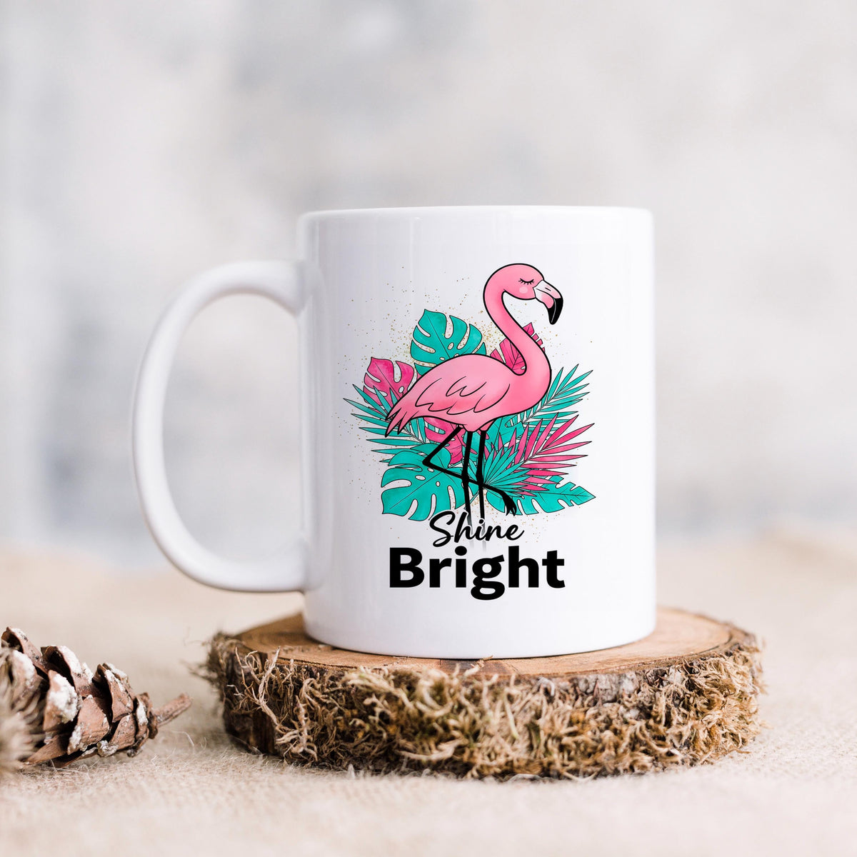White ceramic mug with pink flamingo graphic and “Shine Bright” wording