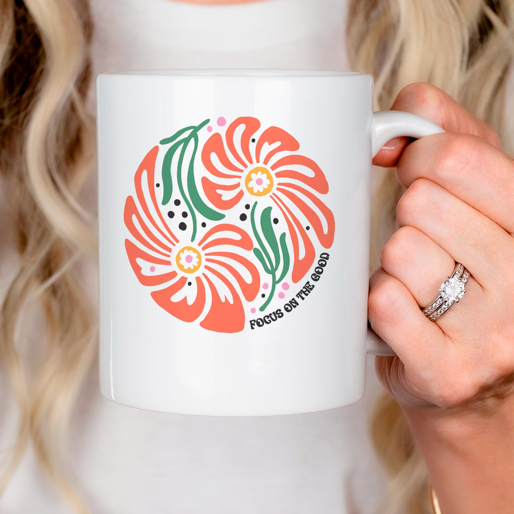 White ceramic mug with coral-and-green floral print and small motivational text