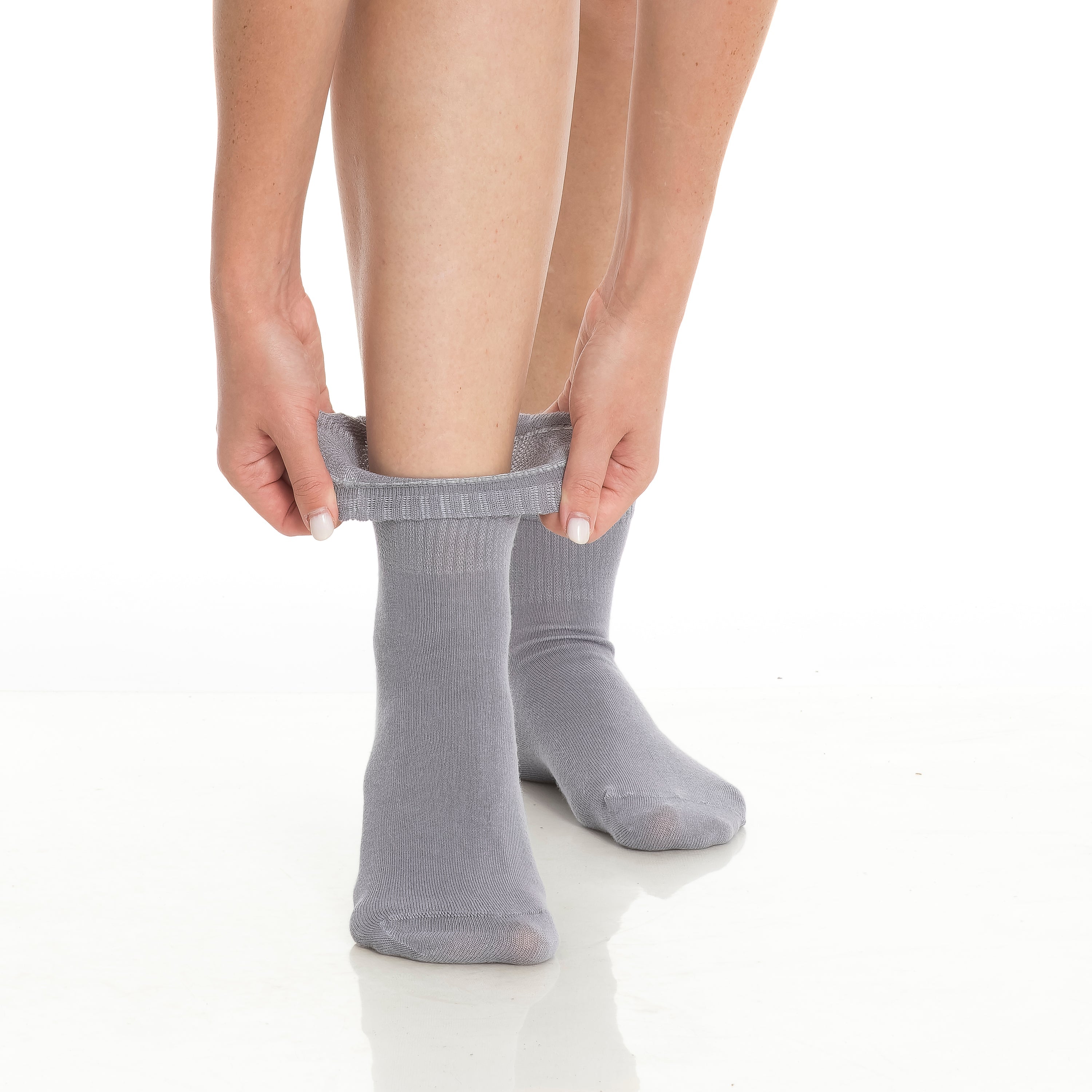 Gray bamboo diabetic ankle socks on feet, hands adjusting cuffs