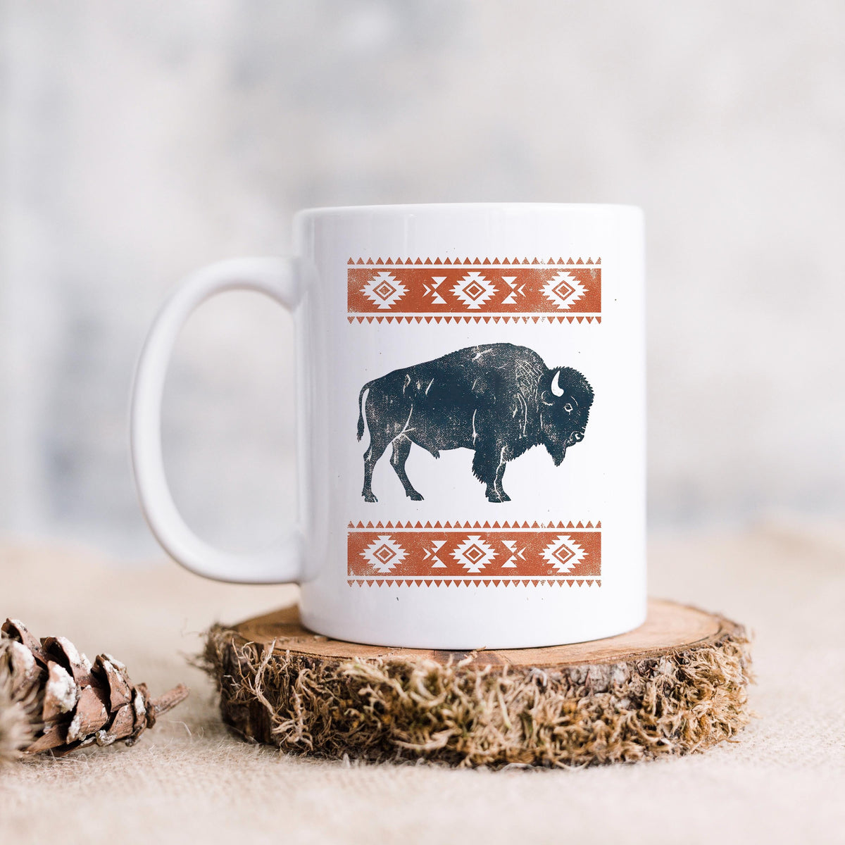 White ceramic mug with black bison graphic and orange patterned band