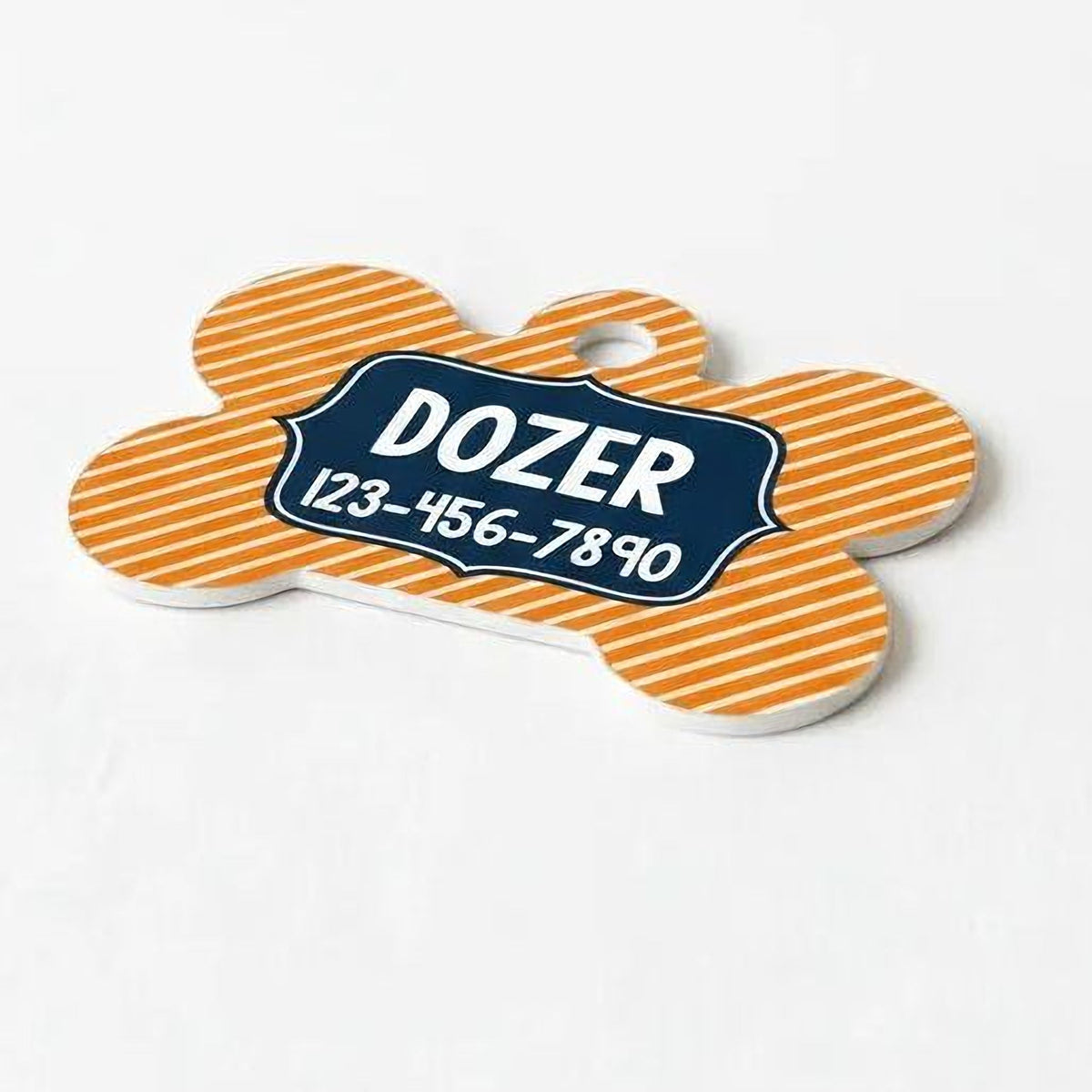 Orange bone-shaped dog tag with striped background and blue ID panel: DOZER 123-456-7890