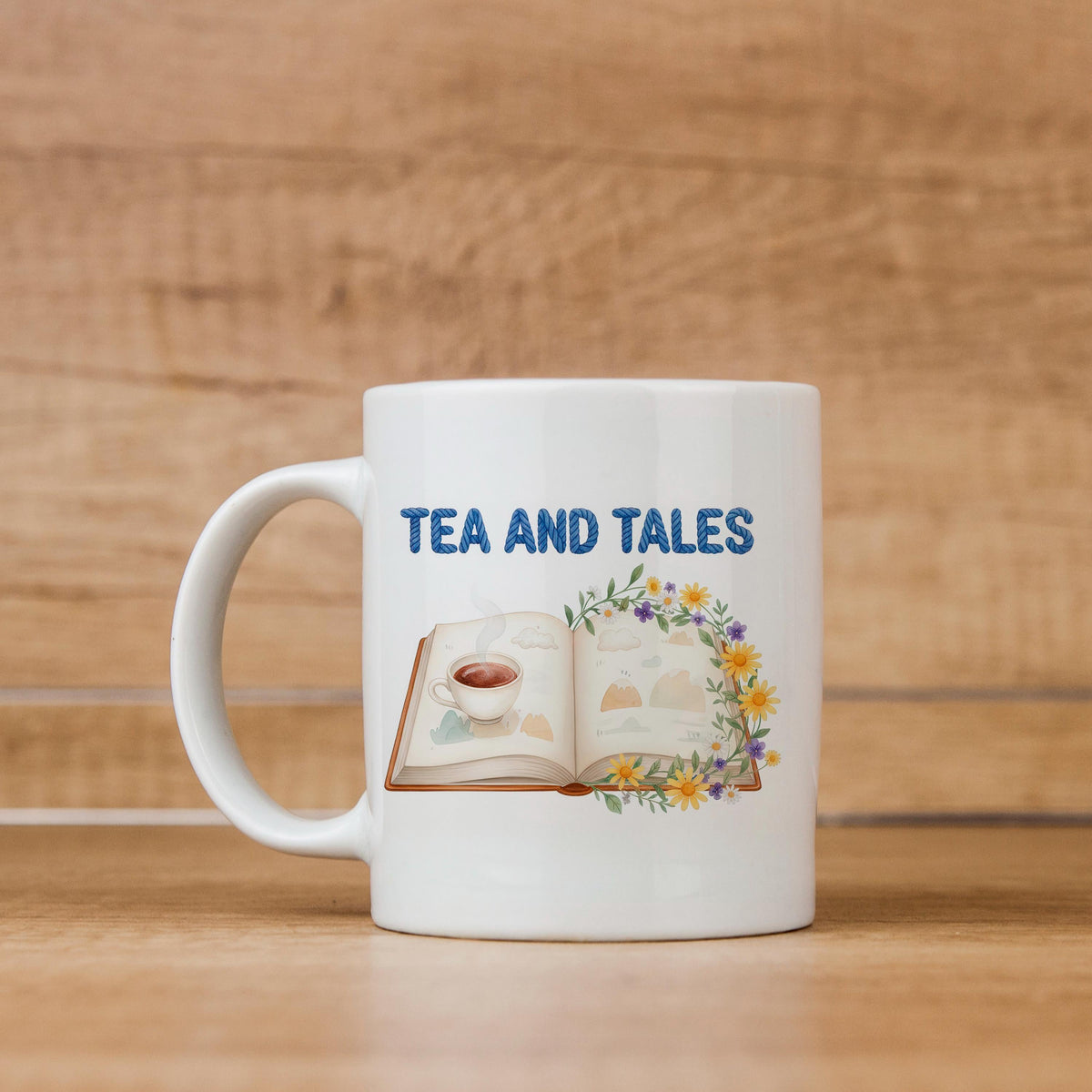 White ceramic mug with "TEA AND TALES" lettering and open book with floral graphic