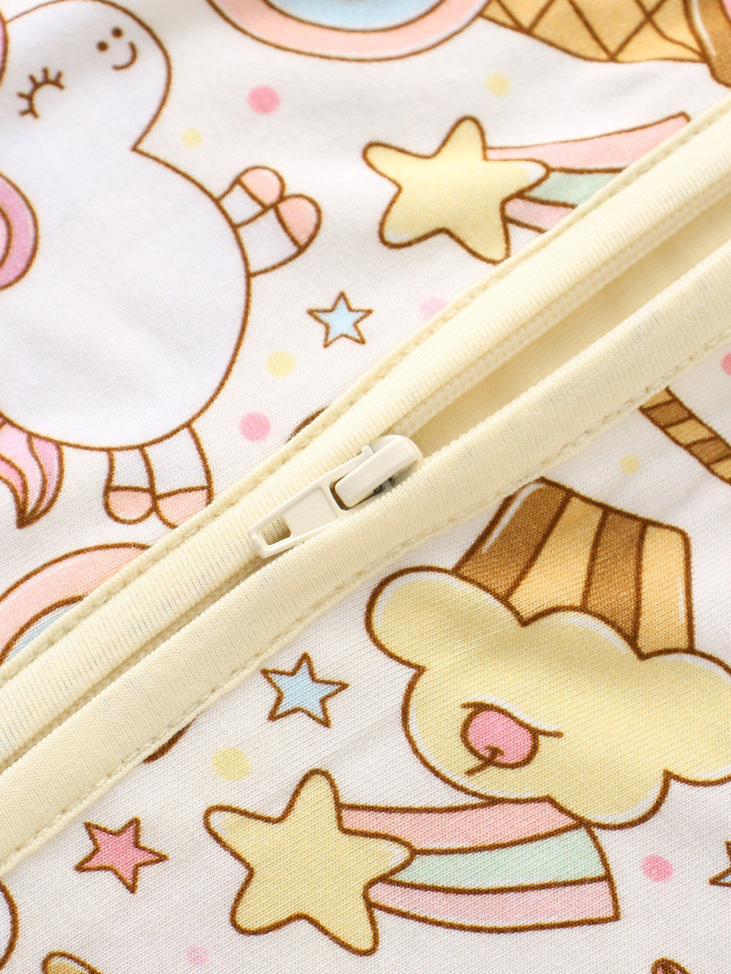 Close-up of zipper on a cream-trim baby romper with rainbow snacks print