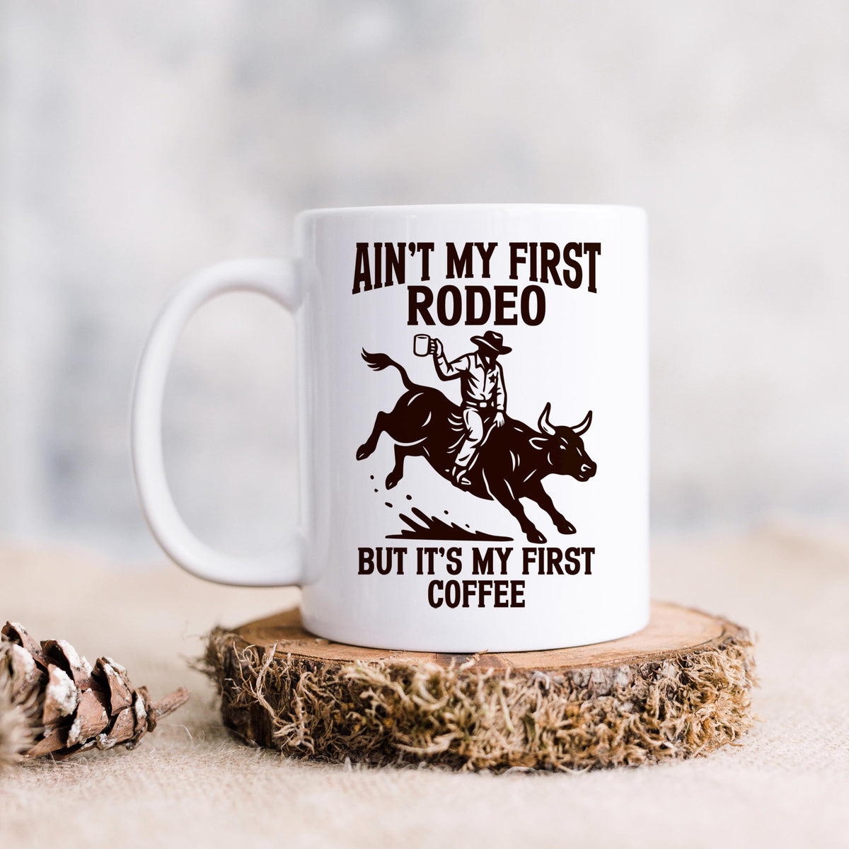 White ceramic coffee mug on a round coaster with rodeo quote and bull rider.