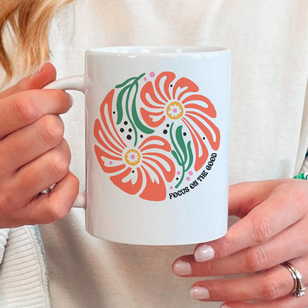White ceramic mug with coral-and-green floral print and motivational text