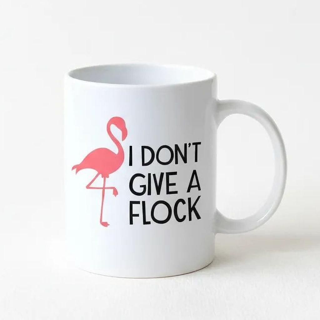 White ceramic coffee mug with pink flamingo and 'I DON'T GIVE A FLOCK' print