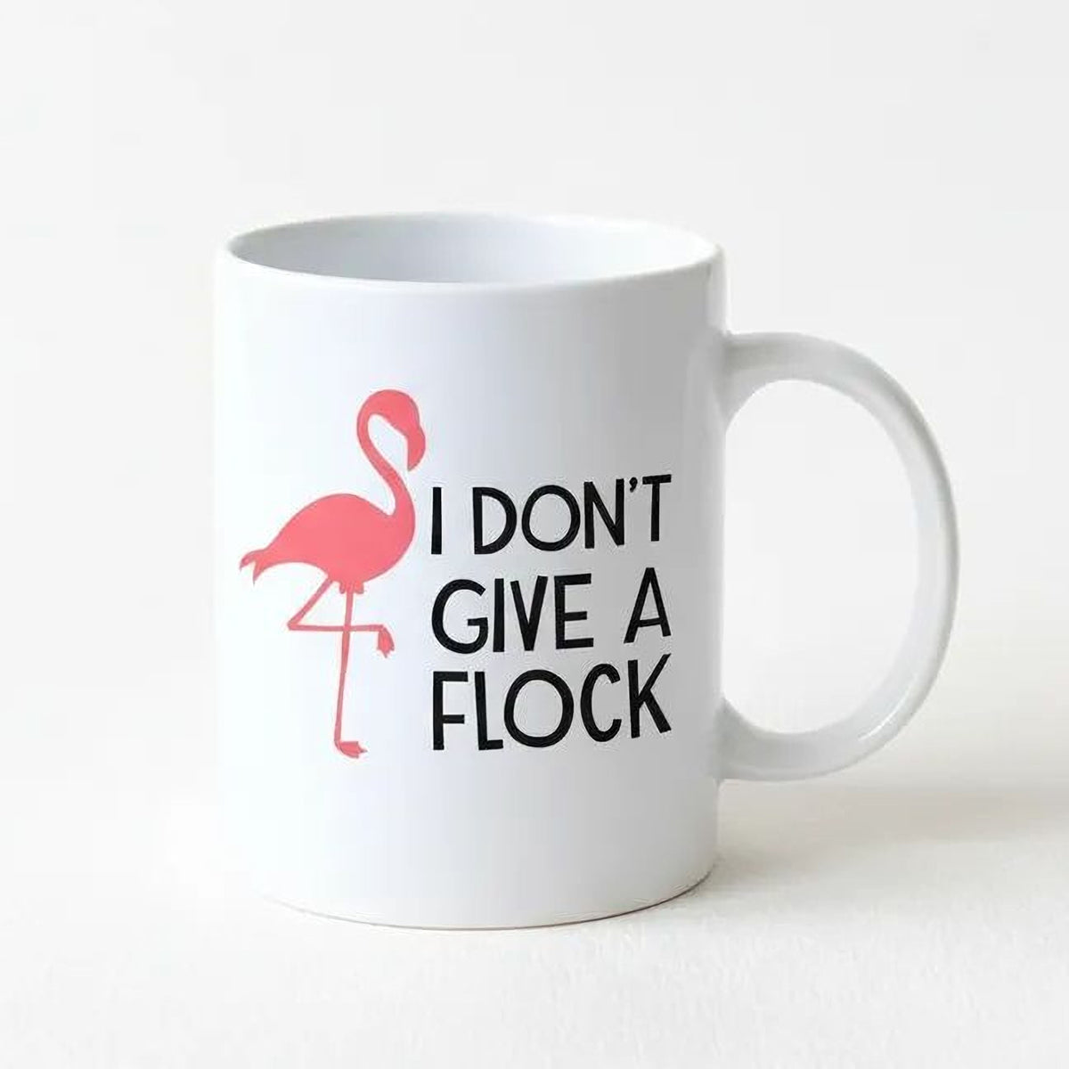 White ceramic coffee mug with pink flamingo and 'I DON'T GIVE A FLOCK' print