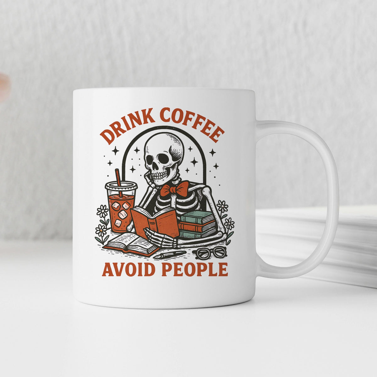 White coffee mug featuring a skeleton with books and red 'Avoid people' text
