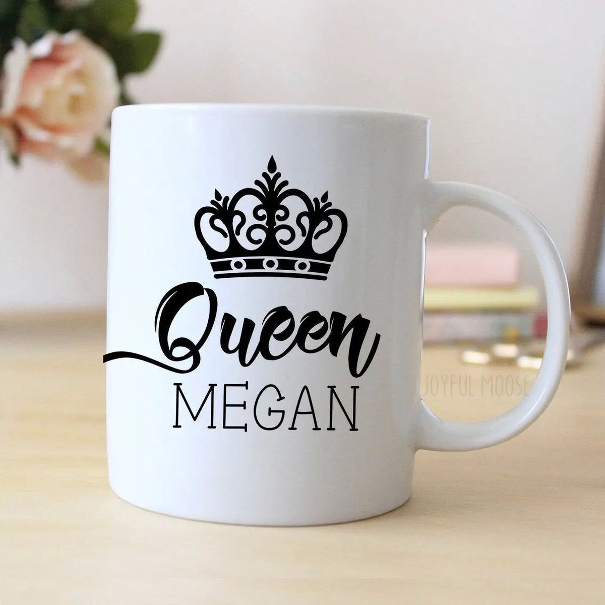 White ceramic mug with black crown and “Queen MEGAN” graphic, angled view with handle.