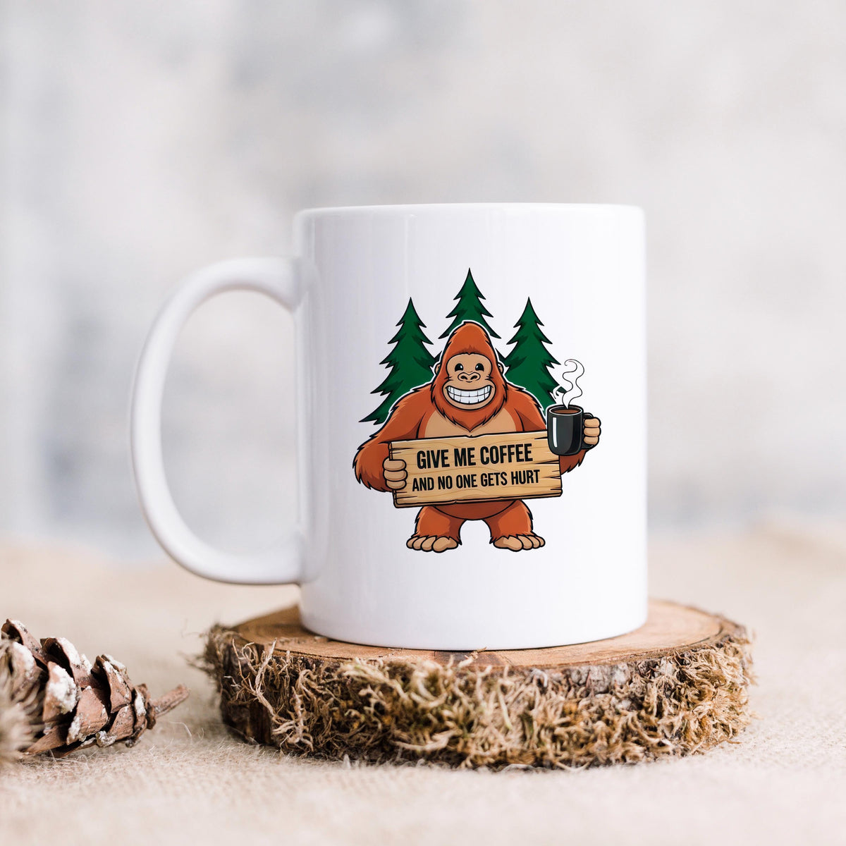 White ceramic coffee mug with Bigfoot graphic holding sign and steaming cup.