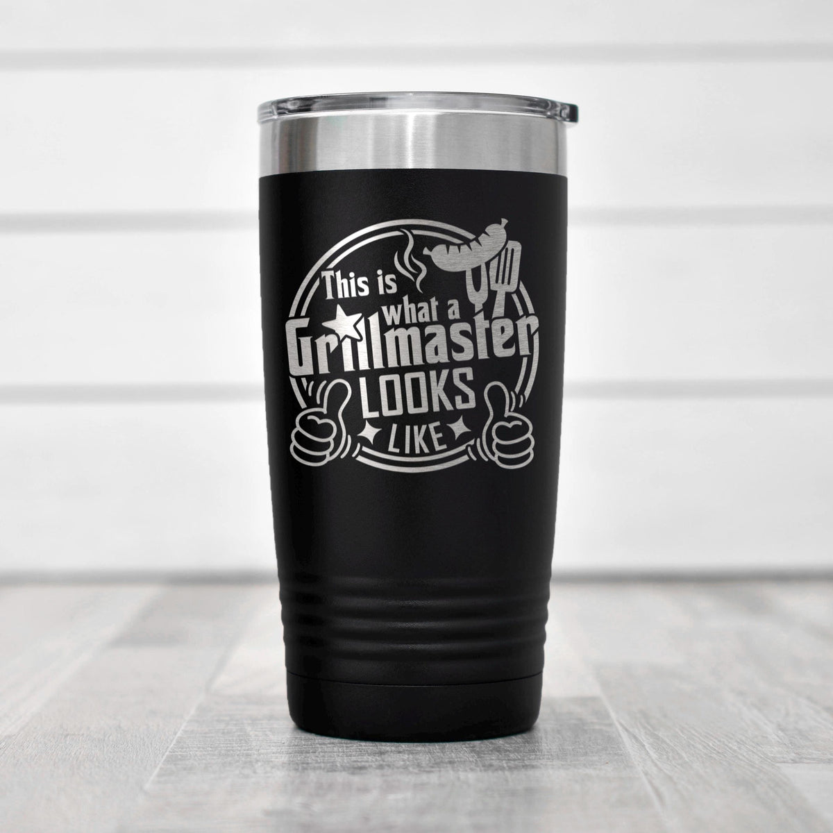 Black insulated stainless steel tumbler on tabletop with Grillmaster logo and lid