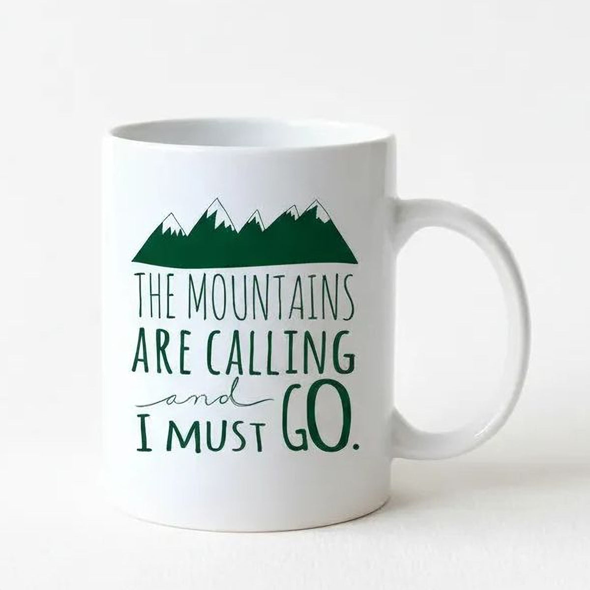 White ceramic coffee mug with green mountain graphic and text design on front
