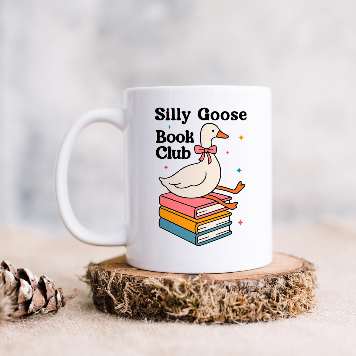 White ceramic mug on a coaster with cartoon goose and stacked books design.