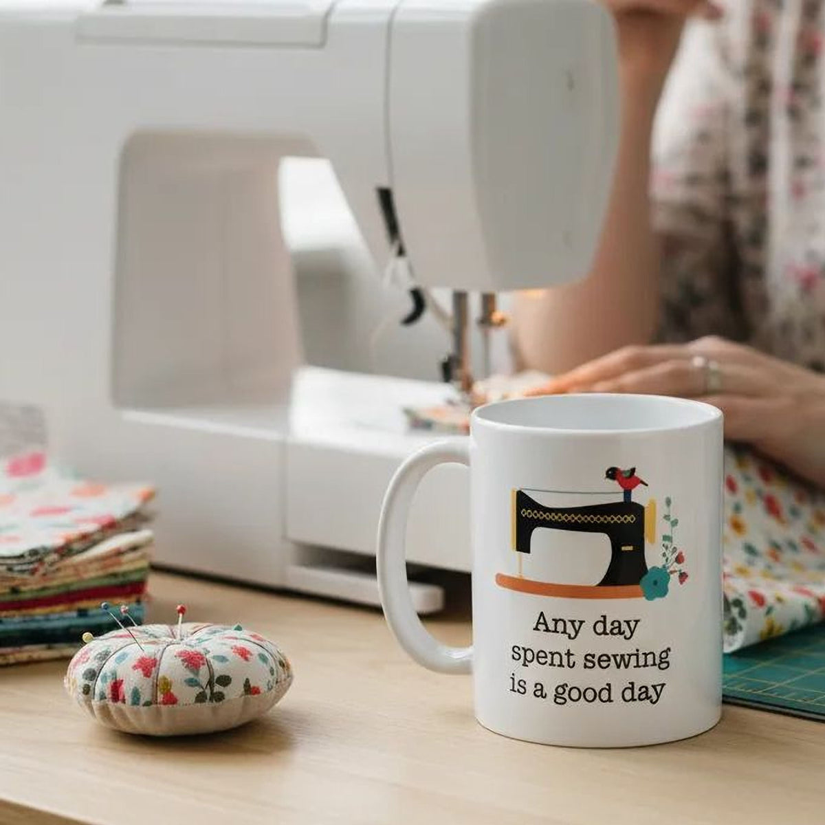 White sewing-themed coffee mug with sewing machine illustration and quote text