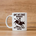 White ceramic coffee mug with cowboy rodeo quote and illustrated bull rider.