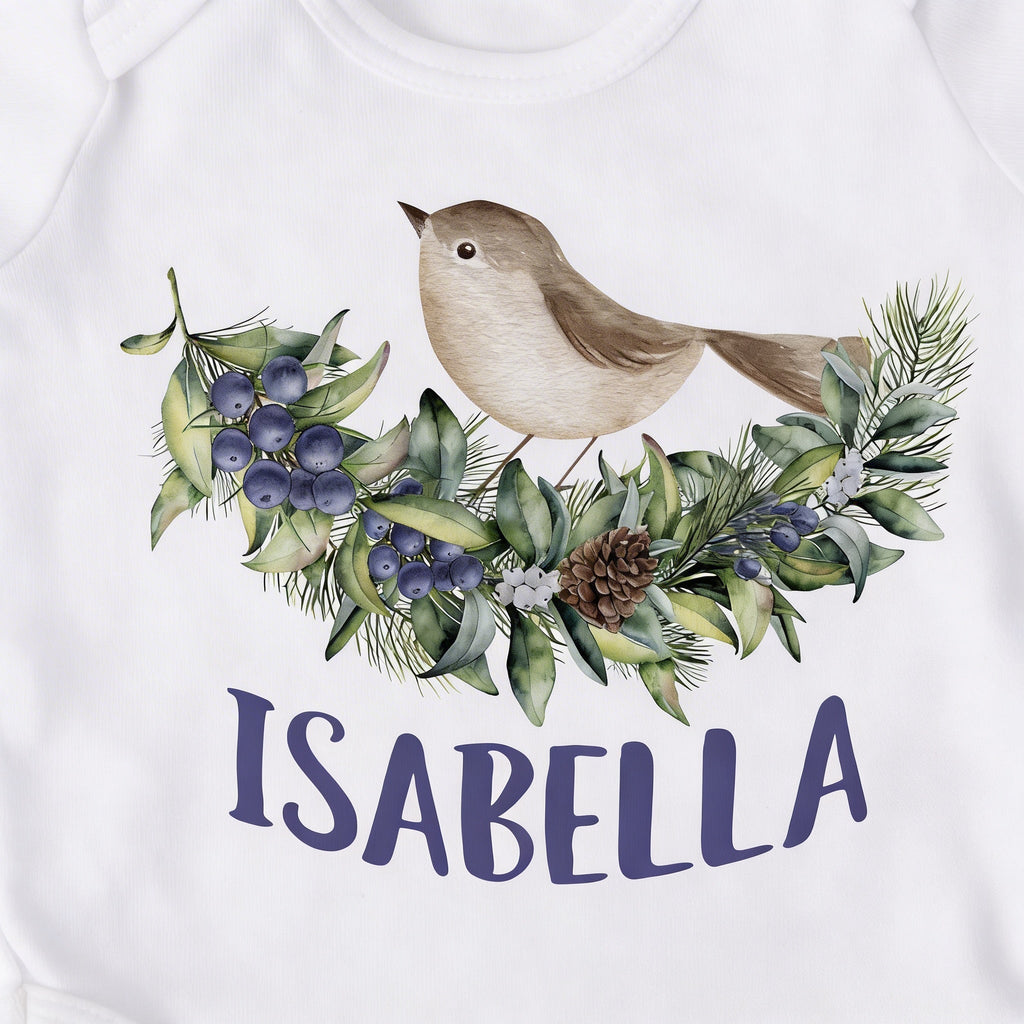 White baby bodysuit close-up: woodland bird with blue-violet floral wreath and 'ISABELLA'