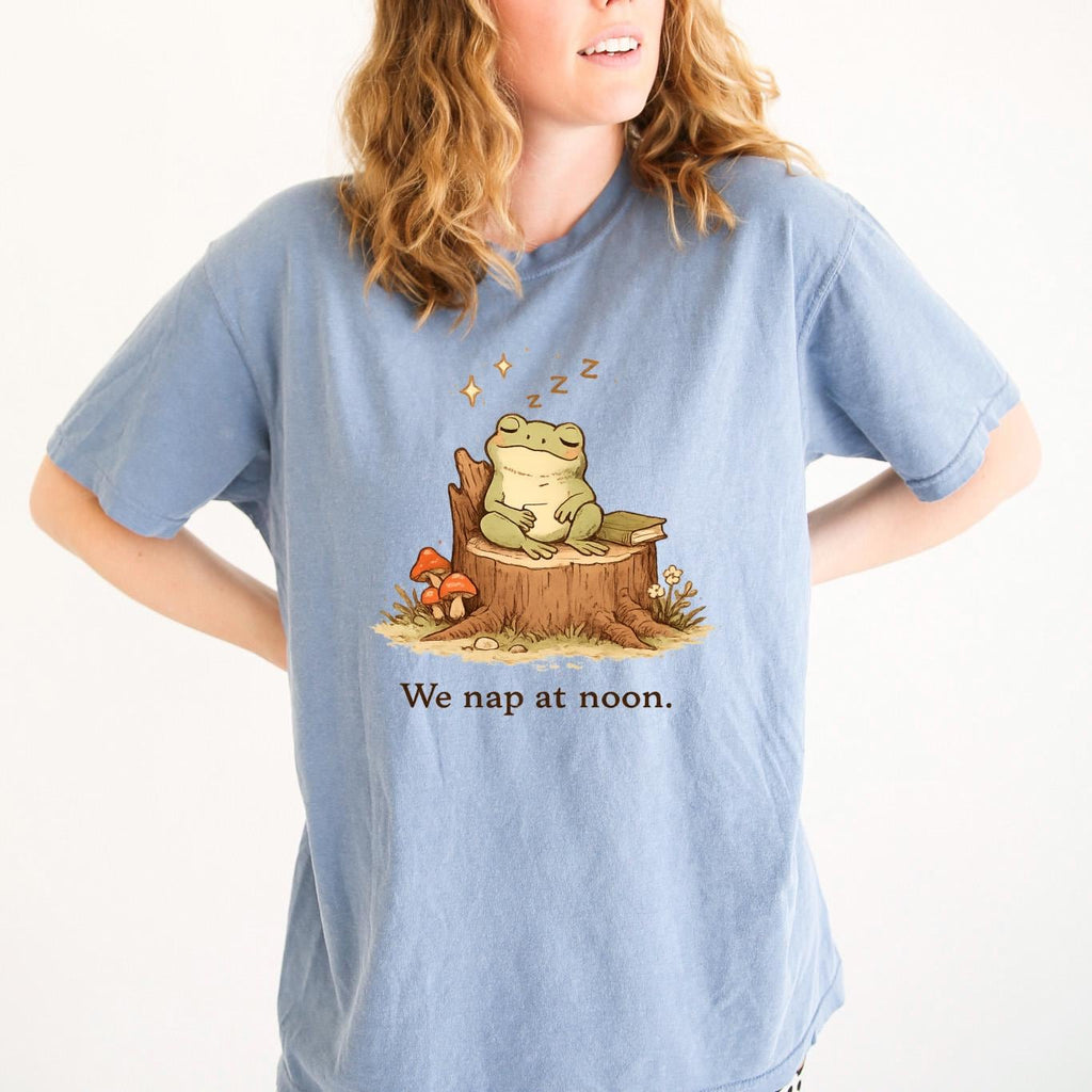 Blue T-shirt with sleeping frog graphic and text “We nap at noon.”