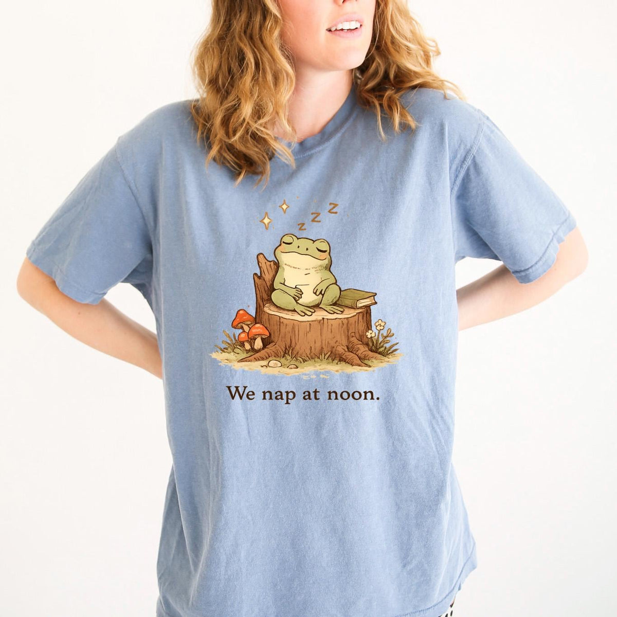 Blue T-shirt with sleeping frog graphic and text “We nap at noon.”