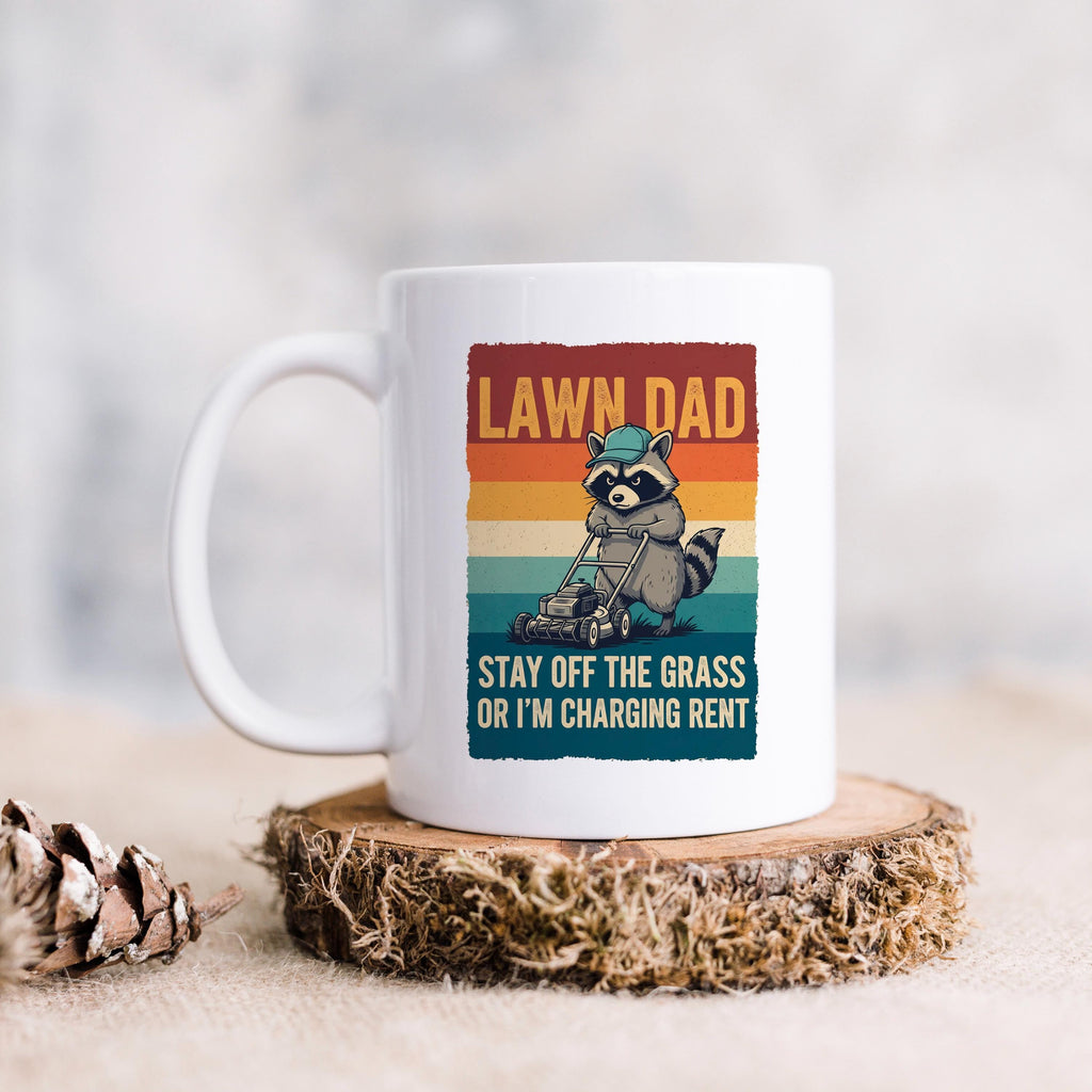 White coffee mug with raccoon mowing graphic and “LAWN DAD” on striped design