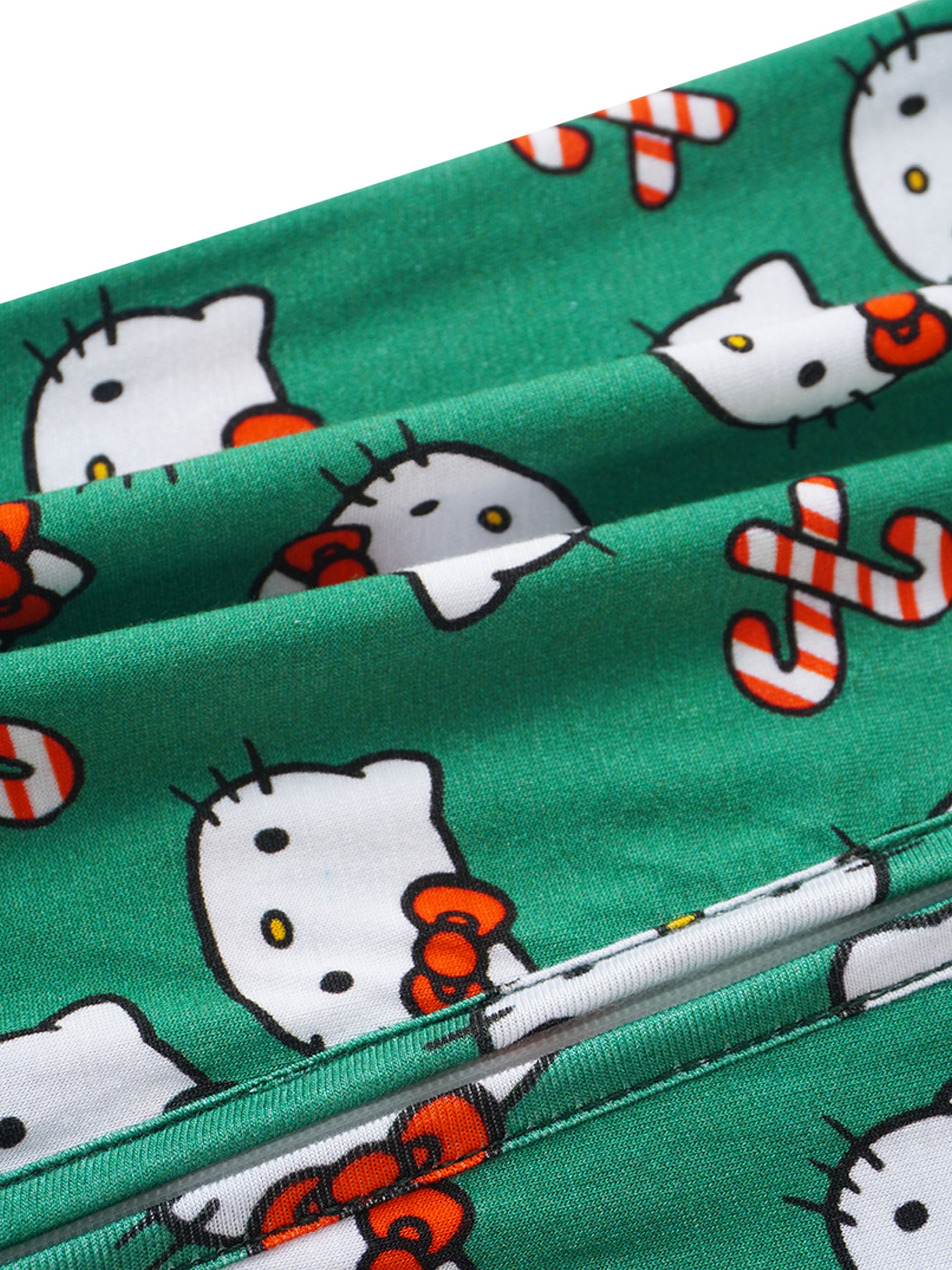 Green baby romper fabric close-up with Hello Kitty faces and peppermint striped details