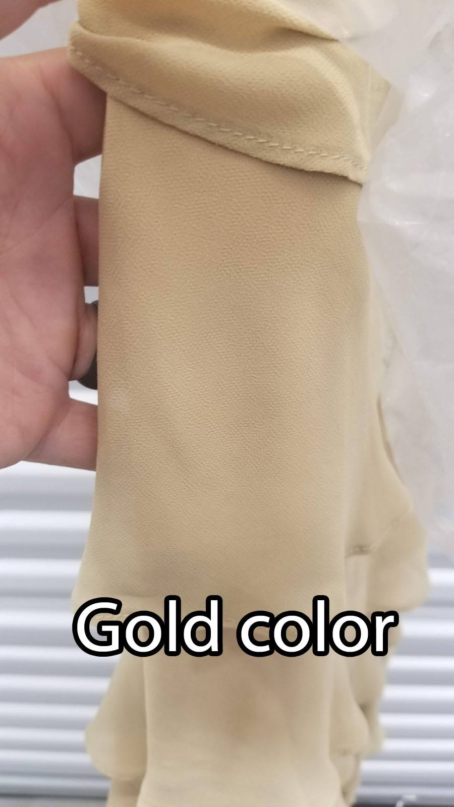 Gold fabric close-up of tiered skirt layers with stitched hem