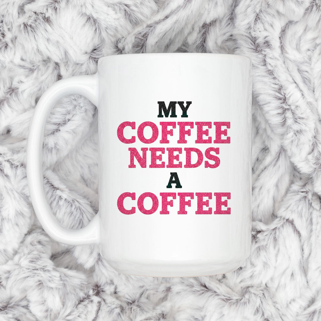 White ceramic coffee mug with "MY COFFEE NEEDS A COFFEE" slogan, close-up