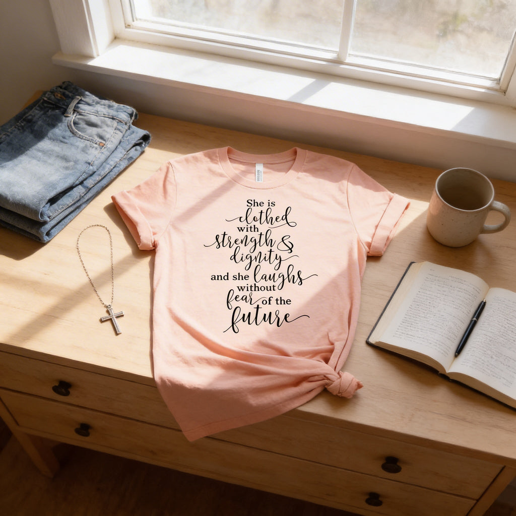 Light peach women's graphic T-shirt with "She is clothed..." verse print front.