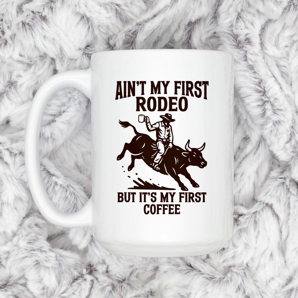 White ceramic coffee mug with cowboy rodeo saying and bull rider illustration.