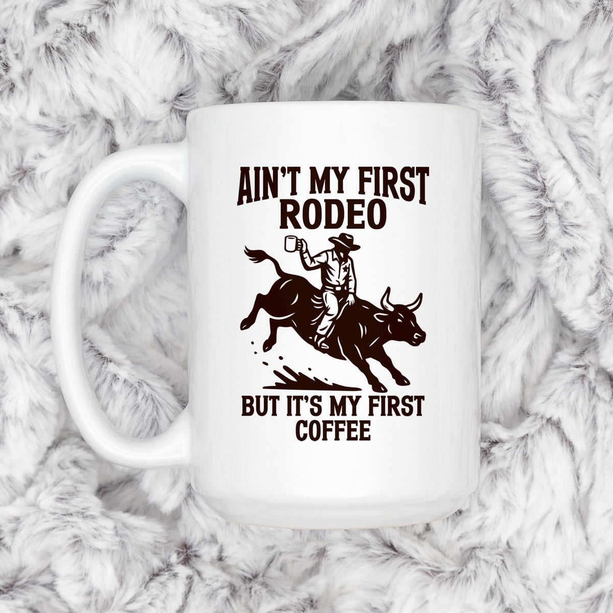 White ceramic coffee mug with cowboy rodeo saying and bull rider illustration.