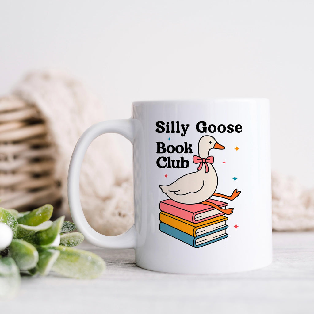 White ceramic mug with goose-and-books design and 'Silly Goose Book Club' text.