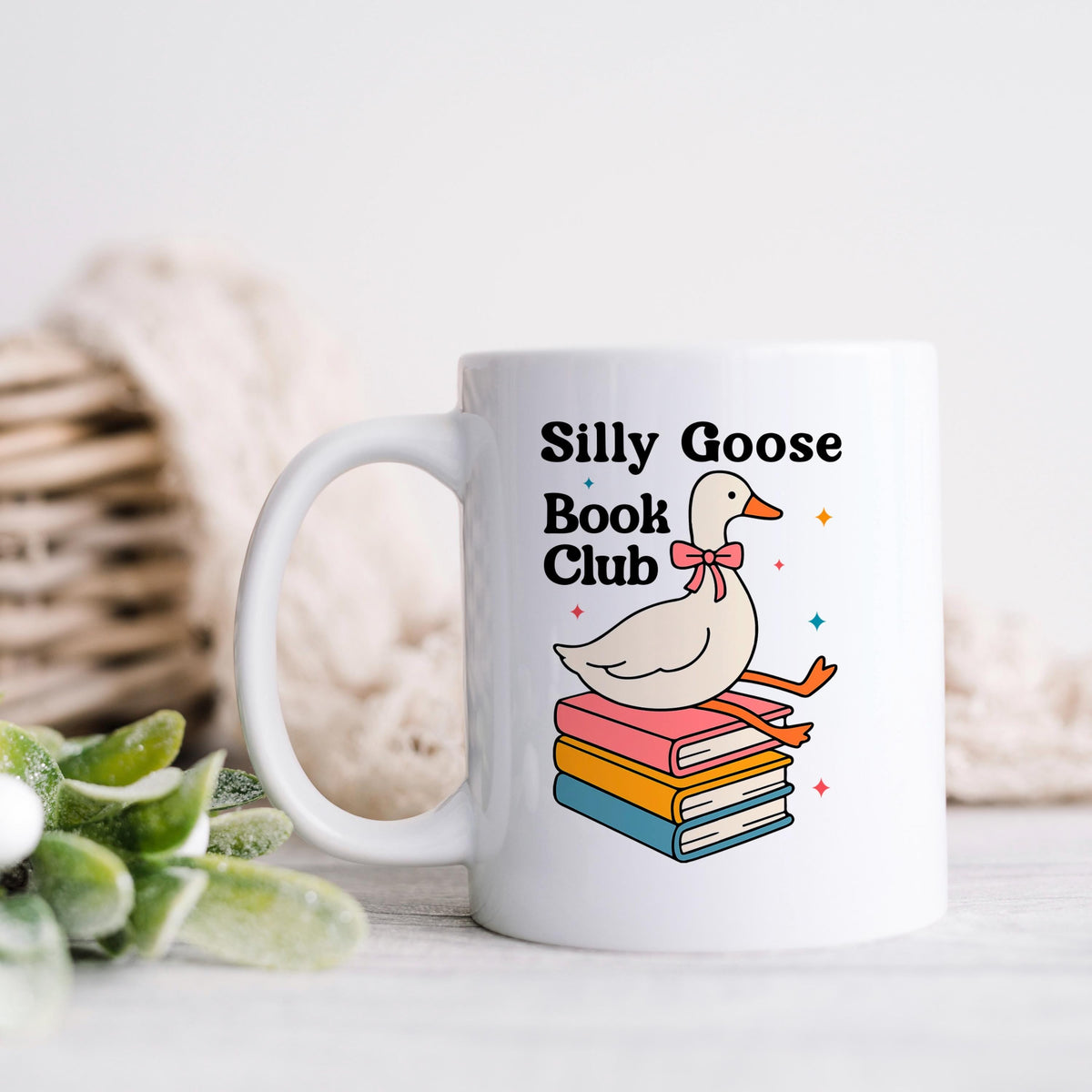 White ceramic mug with goose-and-books design and 'Silly Goose Book Club' text.
