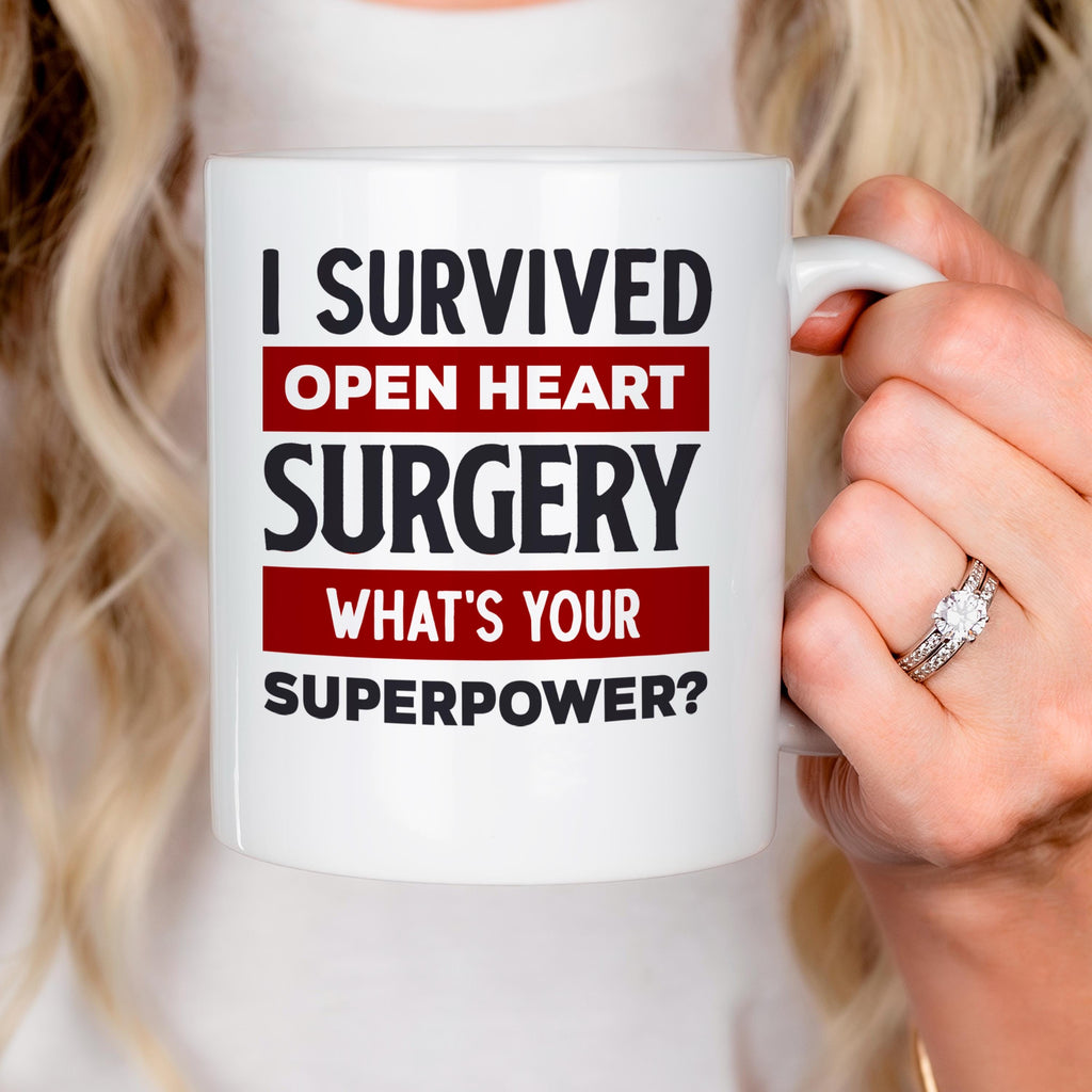 White coffee mug held in hand; text reads: I Survived Open Heart Surgery, What’s Your Superpower?